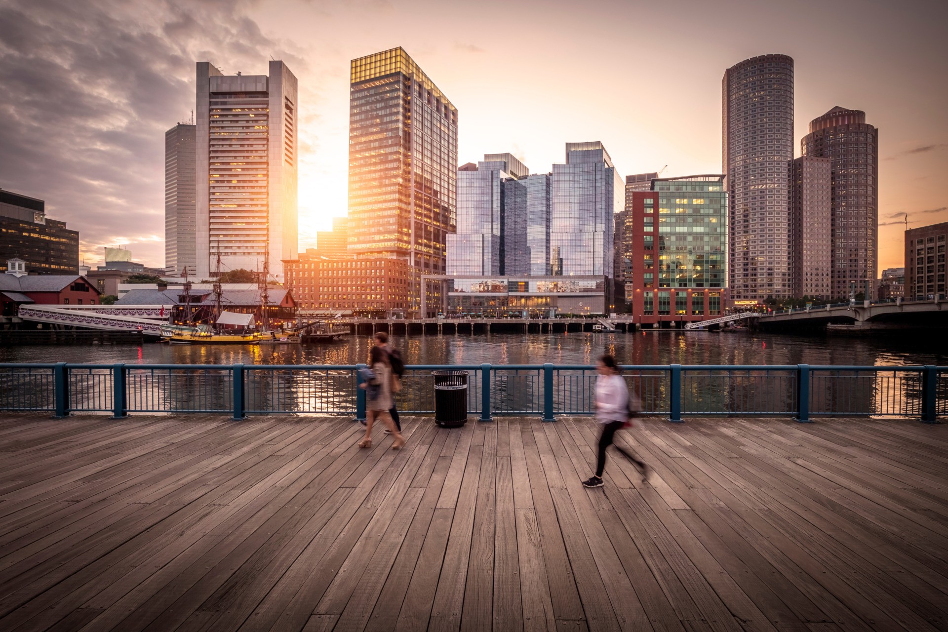 Employee-owned investment firm. People running in Boston Seaport as sun sets in between buildings