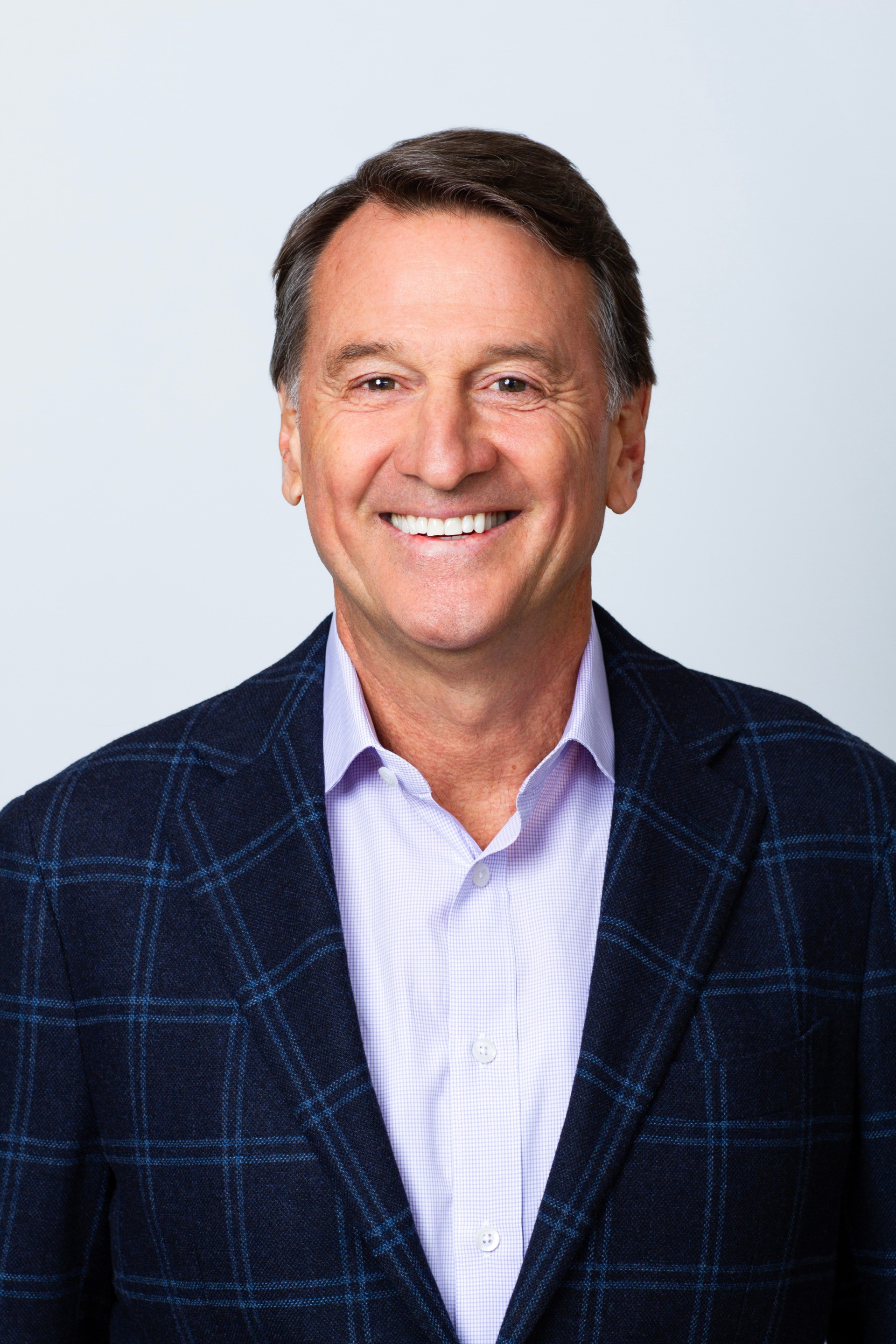 Will Muggia CEO & CIO. Professional Headshot, Will wears a Navy plaid blazer with a blue button-down shirt.