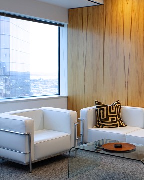 Contact Us. Let’s connect. Two couches in the Westfield Capital office with a wood paneling wall behind one and a window behind the other showing the city skyline.