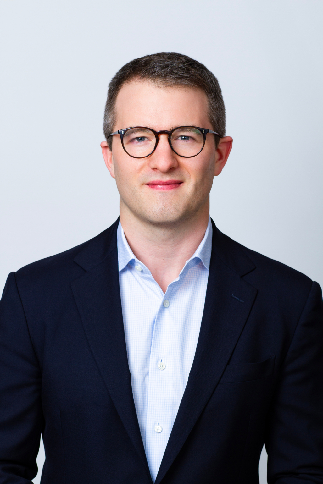 Nate Cunningham Vice President professional headshot. He is wearing a blue button-down with a black blazer.