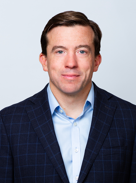 Mike Poe Partner professional headshot. He is wearing a blue button-down shirt with a navy blazer.